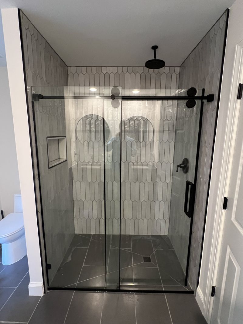 Picket tile shower with black frameless sliding glass and ceiling rain head, bathroom renovation in Montgomery County PA