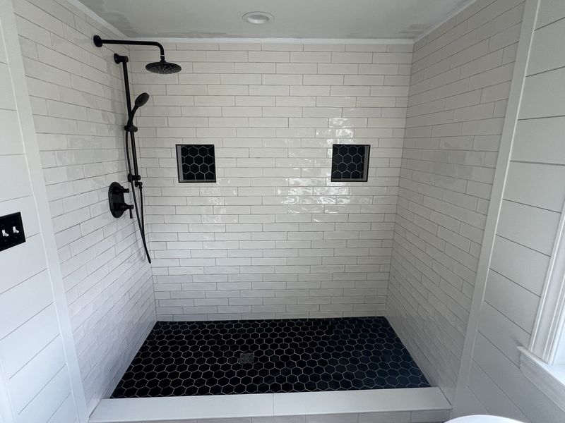 White subway tile shower with black hexagon floor and twin niches, bathroom remodel in Chester County PA