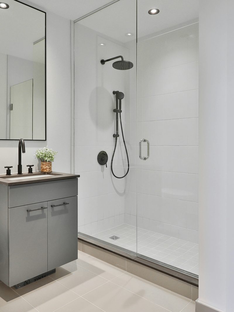 Walk-in shower with panel walls, frameless glass and matte black fixtures — the finish direction of a LuxeDay bathroom